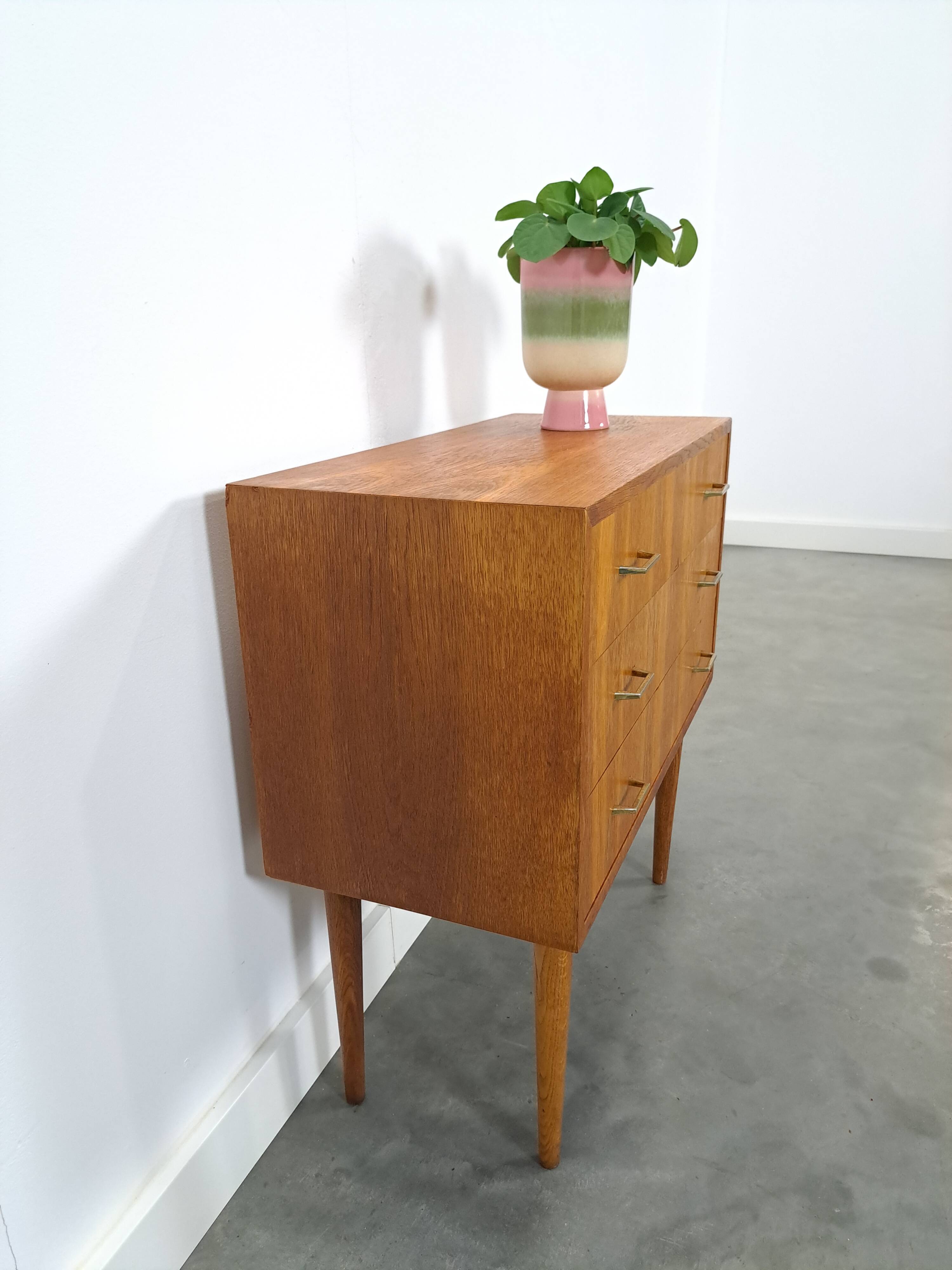 Commode danoise avec de hauts pieds et des poignées dorées.