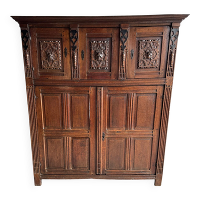 Armoire ancienne en bois foncé sculpté, ornée de motifs floraux sculptés à la main et de poignées en métal.