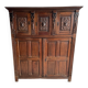Armoire ancienne en bois foncé sculpté, ornée de motifs floraux sculptés à la main et de poignées en métal.