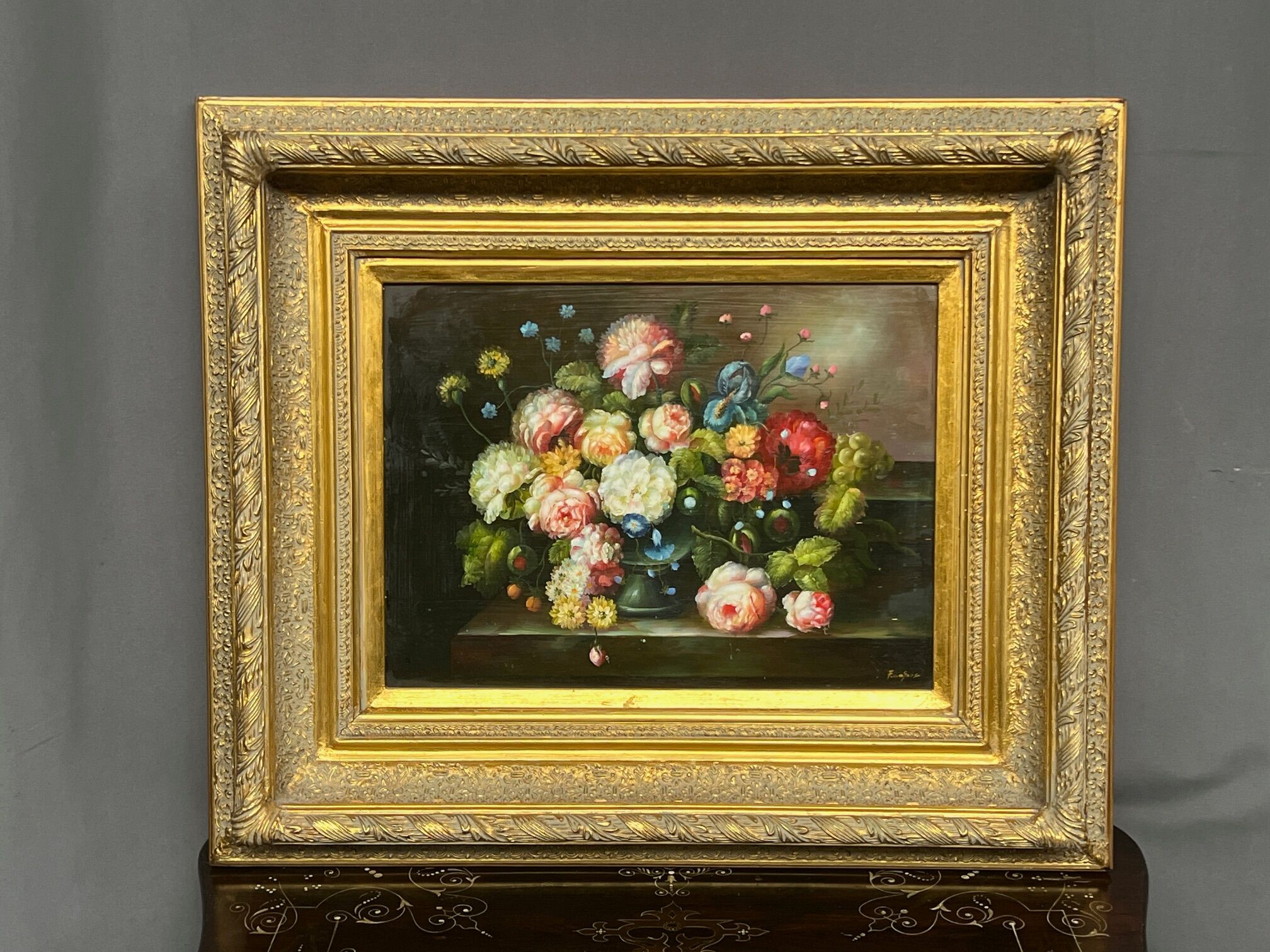 Still life with roses in a beautiful frame on a wooden panel in Flemish style.