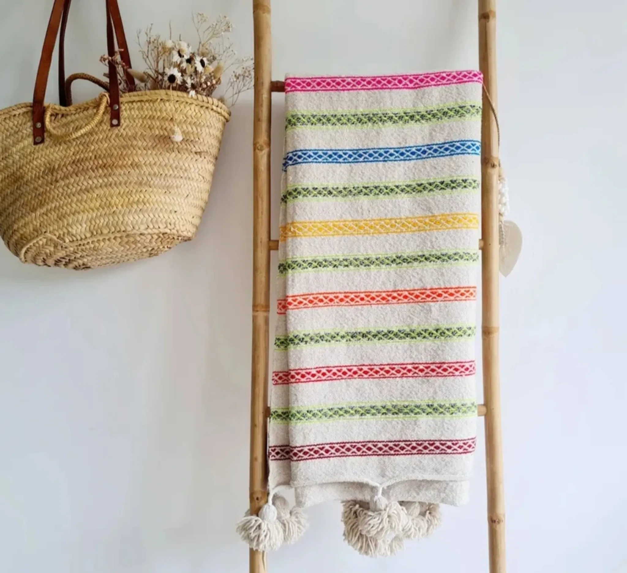 Moroccan plaid made of handwoven wool, decorated with stripes and pom poms.