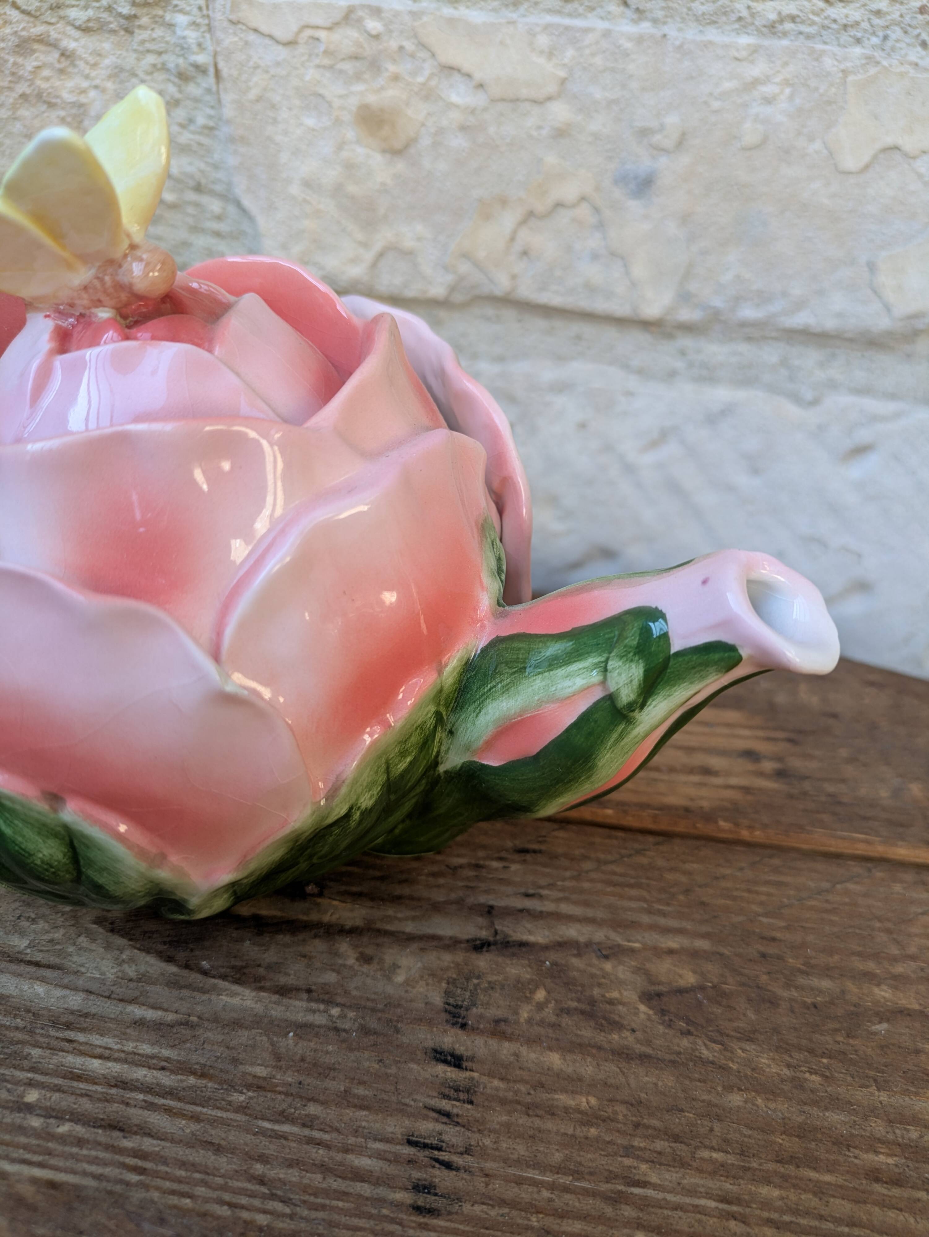 Ceramic teapot in the shape of a rose with a butterfly and raised petals.