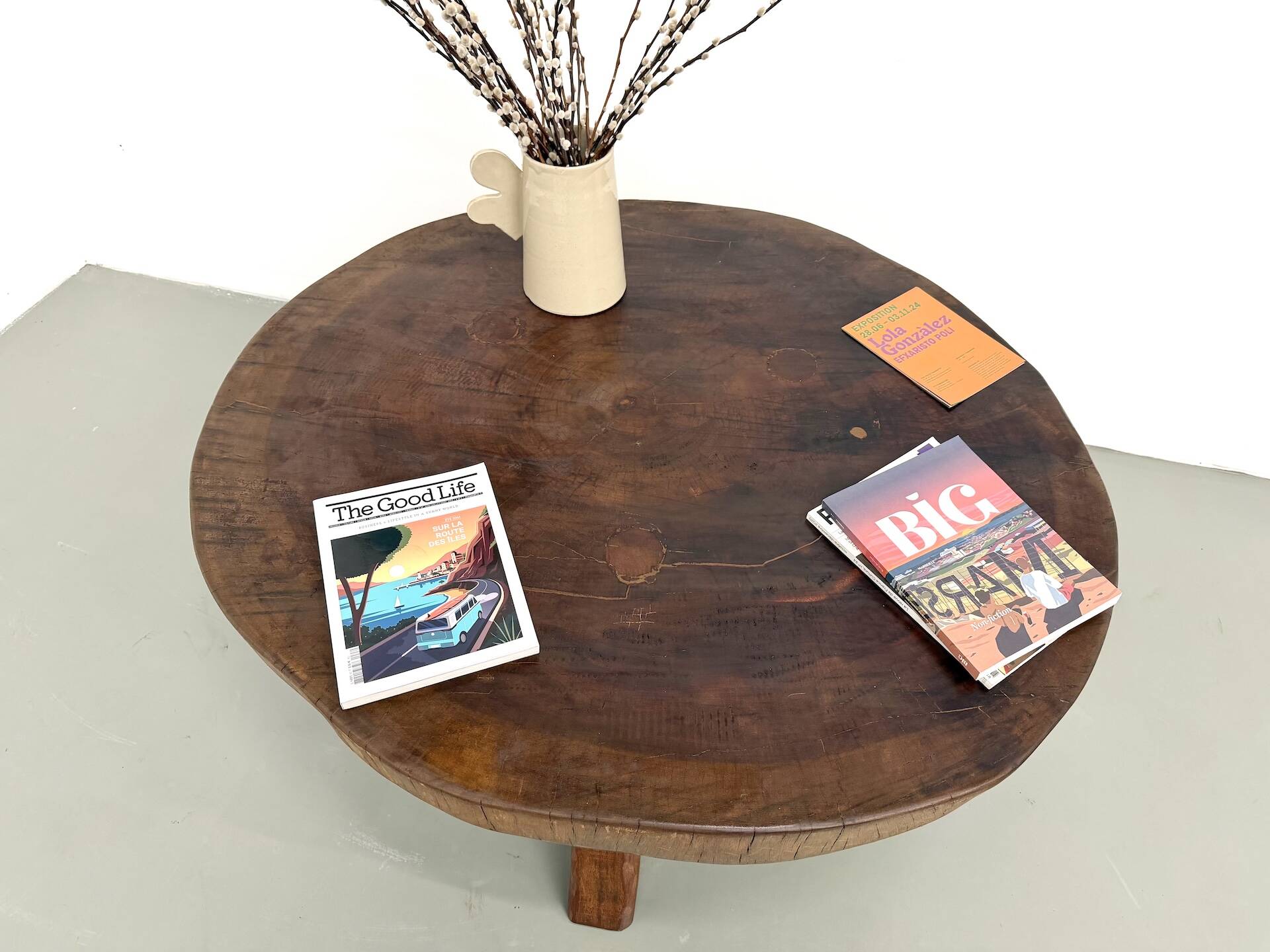 Brutalist coffee table in solid teak, monolithic slab, tripod base.