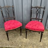 Pair of black lacquered chairs with purple tufted upholstery.