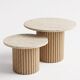 Round nesting coffee table in travertine and raw fluted wood.