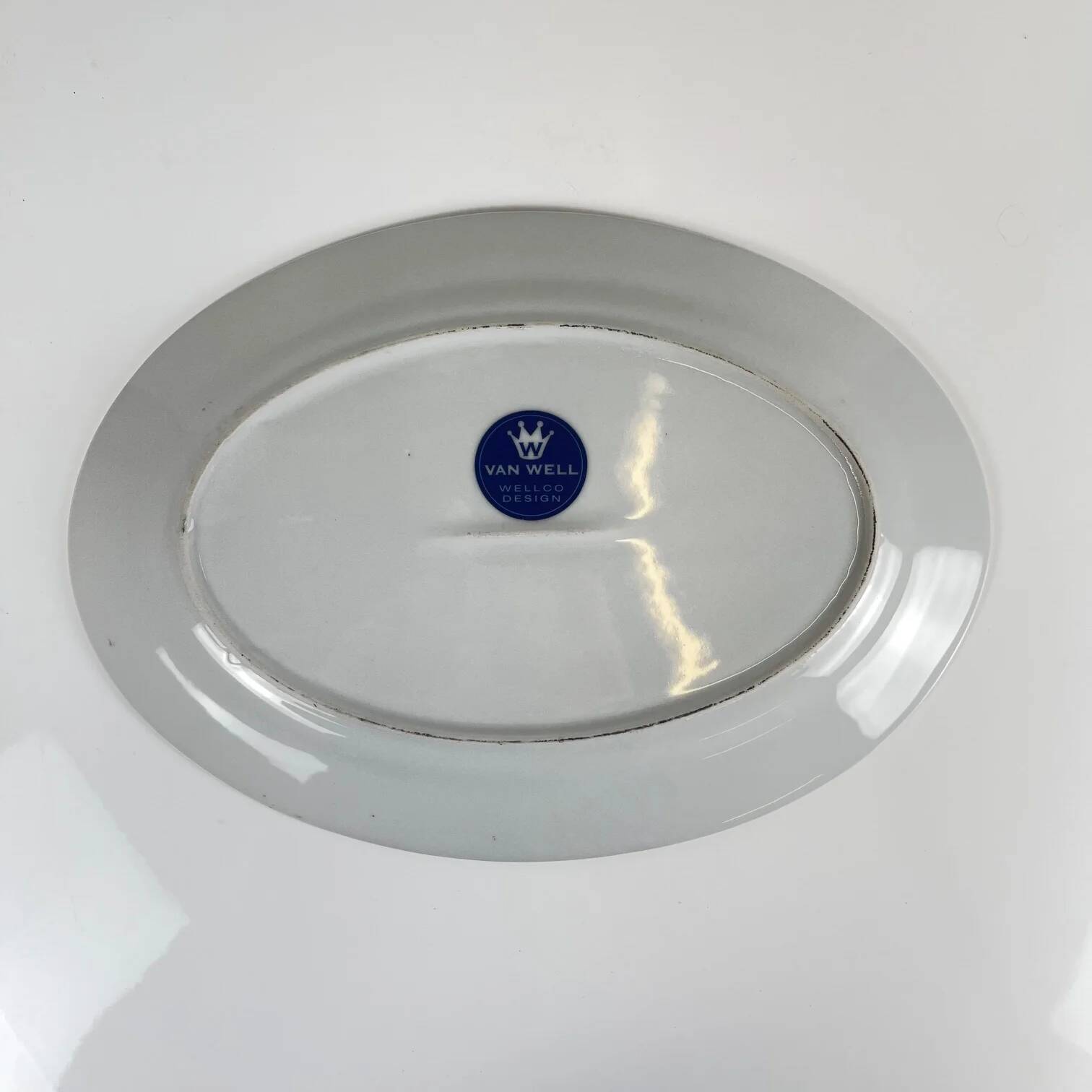 Oval porcelain plate by Van Well, multicoloured geometric border, 1980.