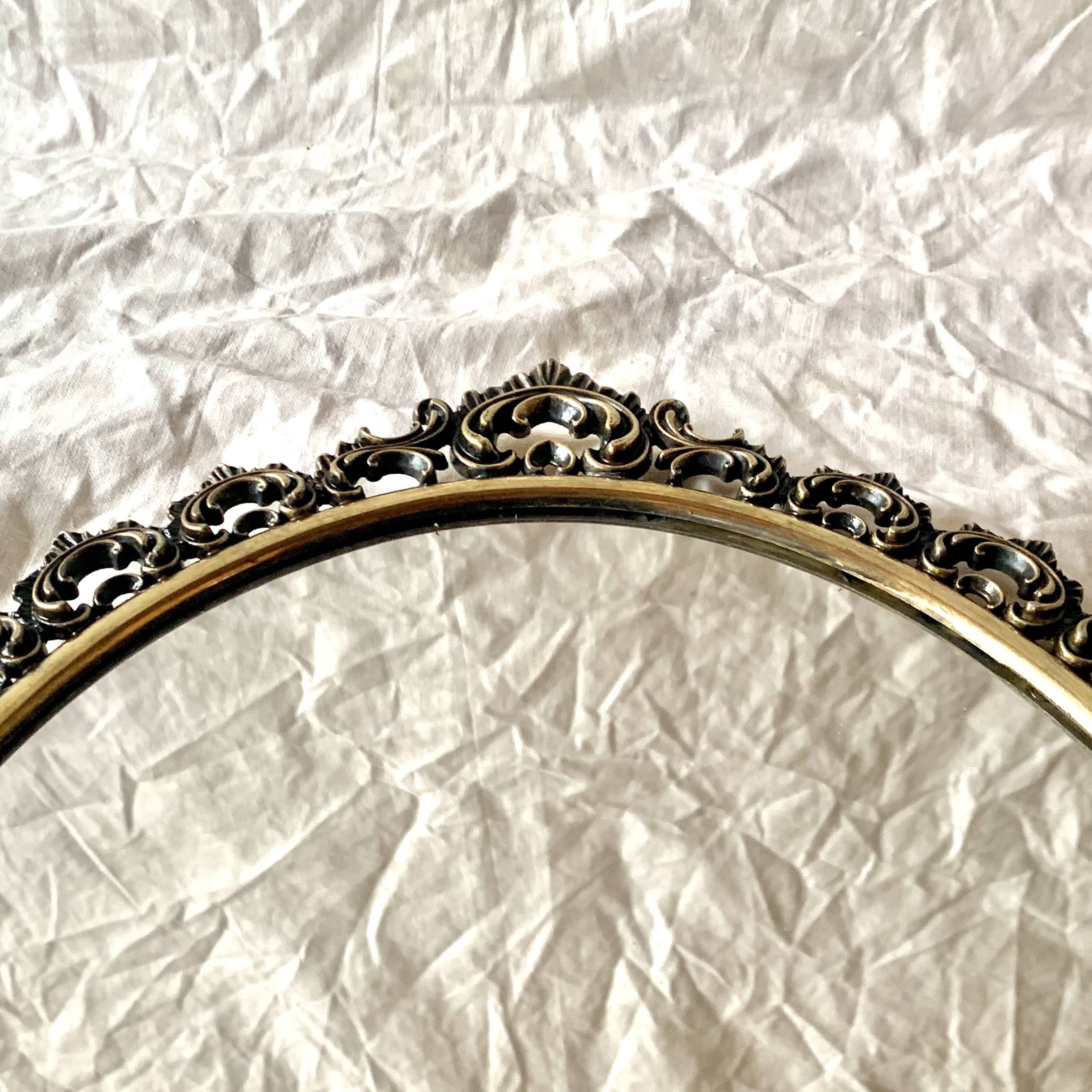 Old oval wall mirror in gilded brass