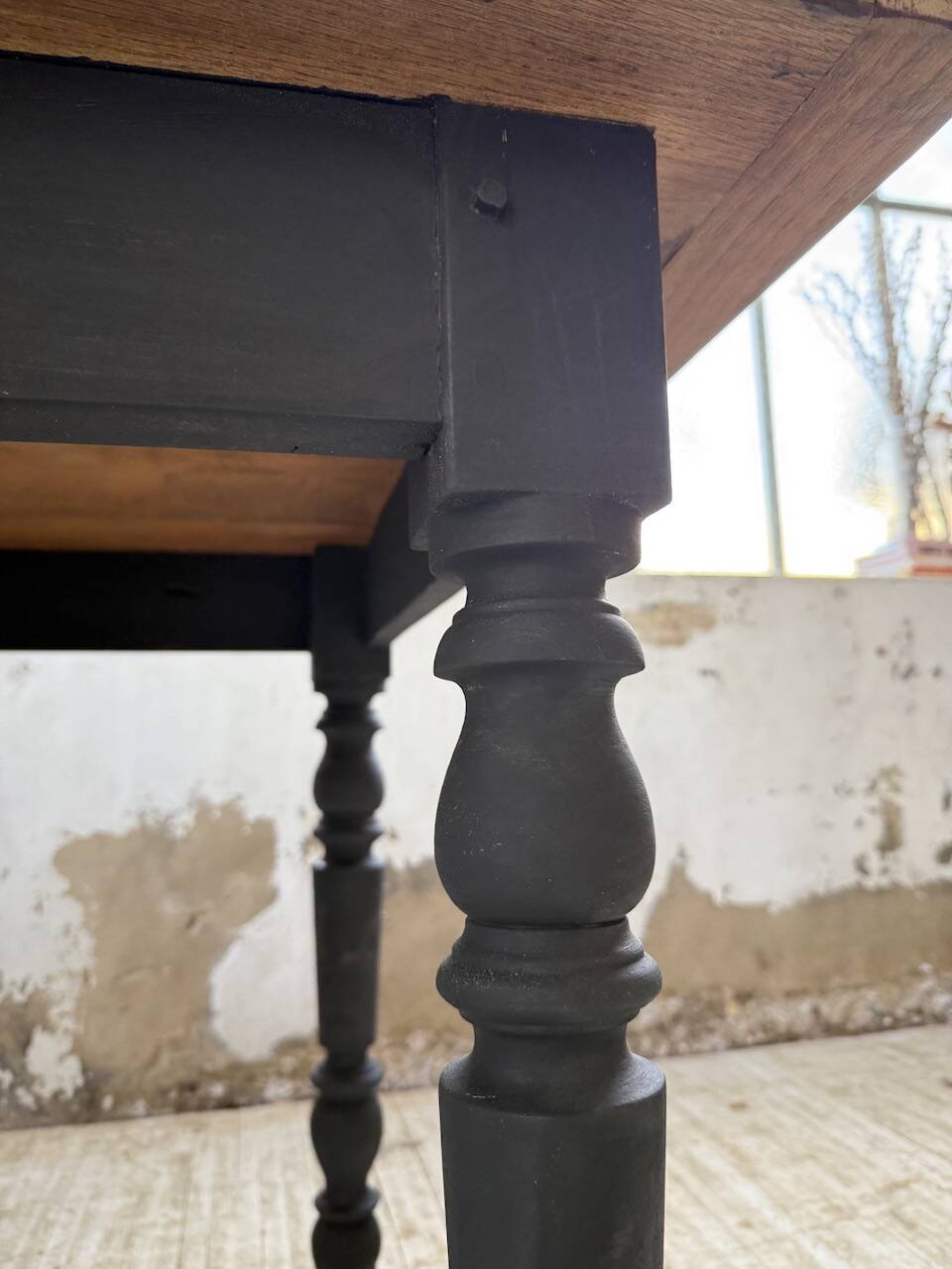Oak farmhouse table with turned black legs.
