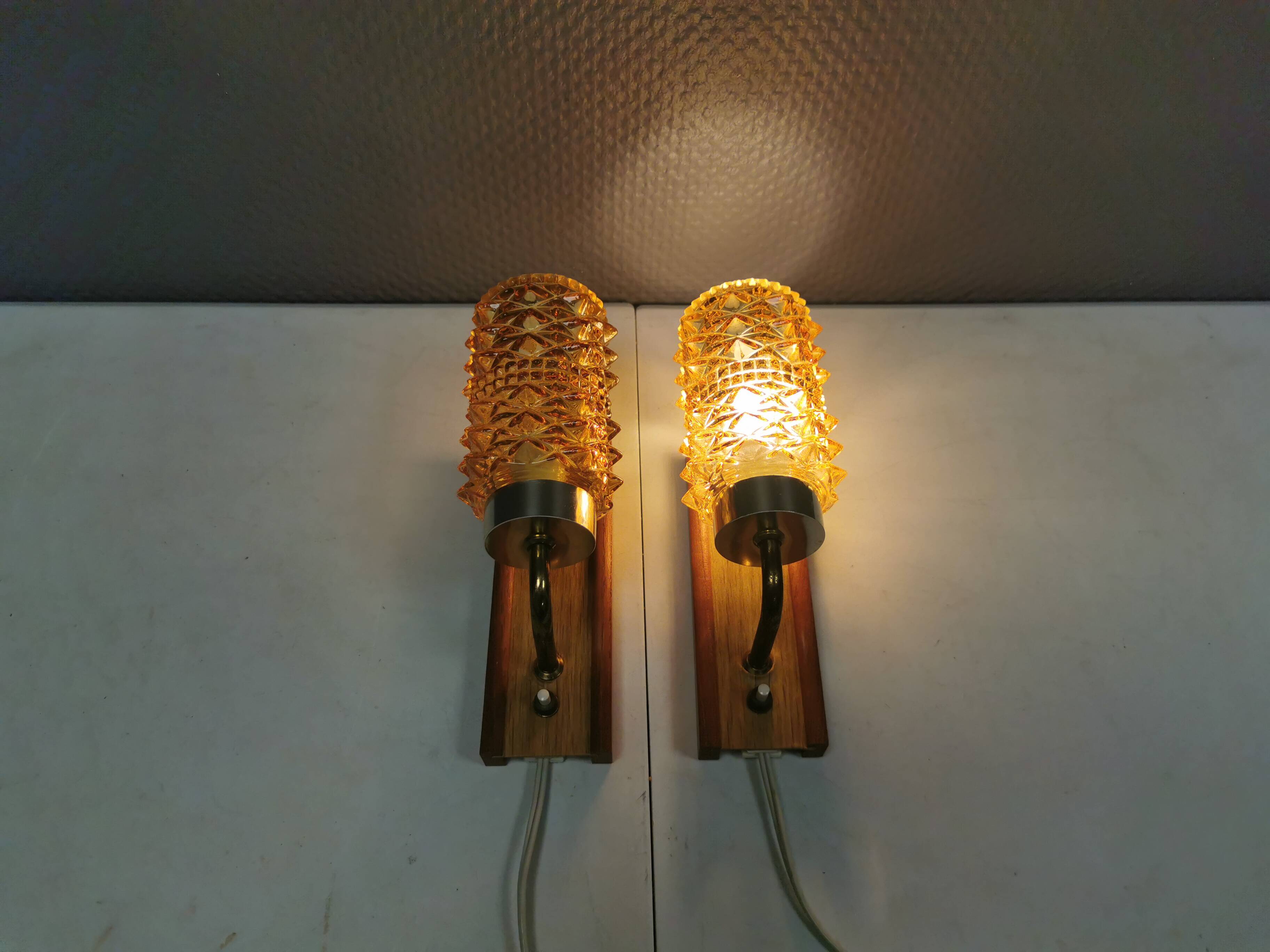 A set of wall lamps in teak wood, with amber colored glass