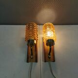 A set of wall lamps in teak wood, with amber colored glass