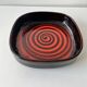 Large decorative ceramic catchall with red and black spiral pattern.