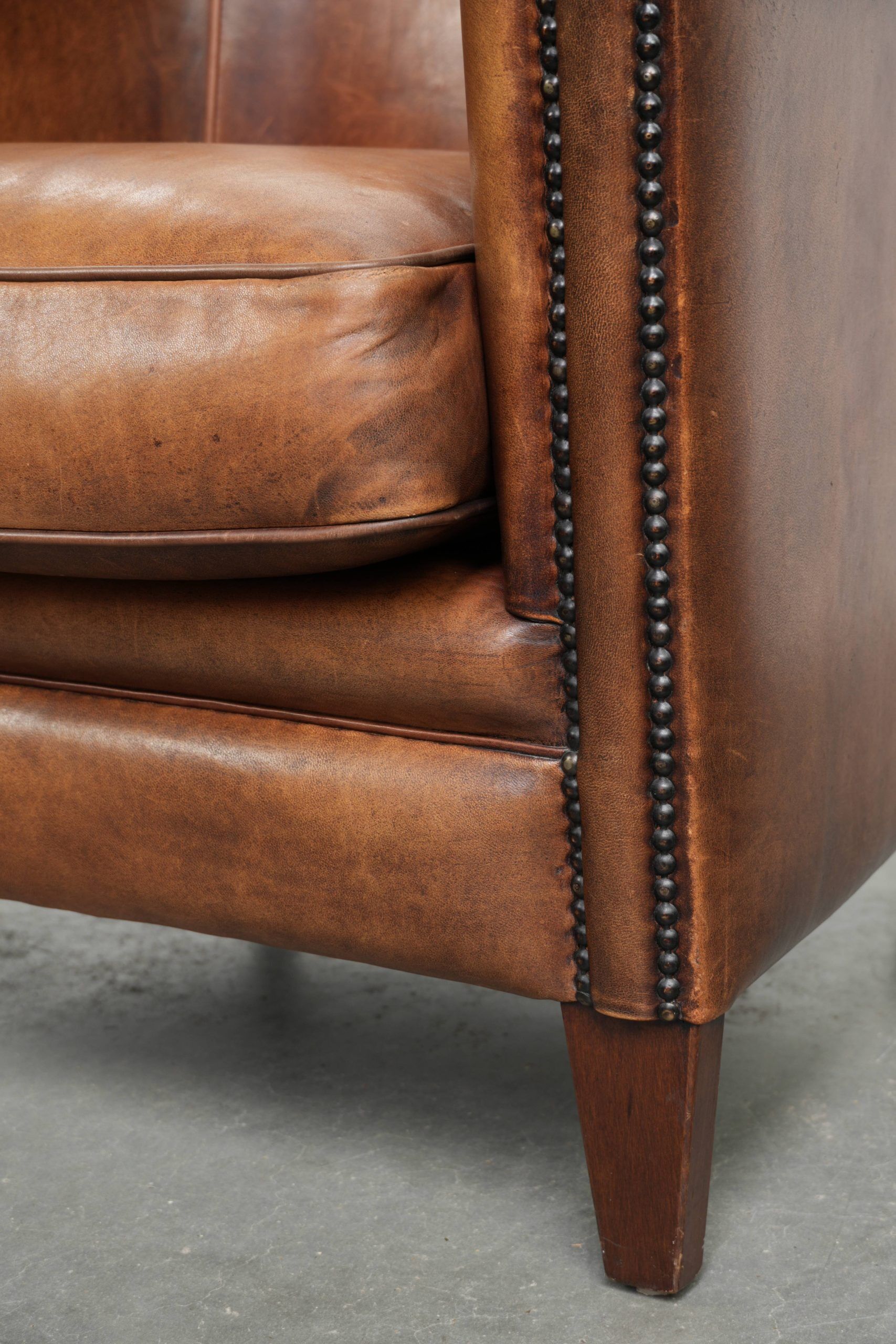 Sheepskin club armchair with a cognac colour finished with decorative nails
