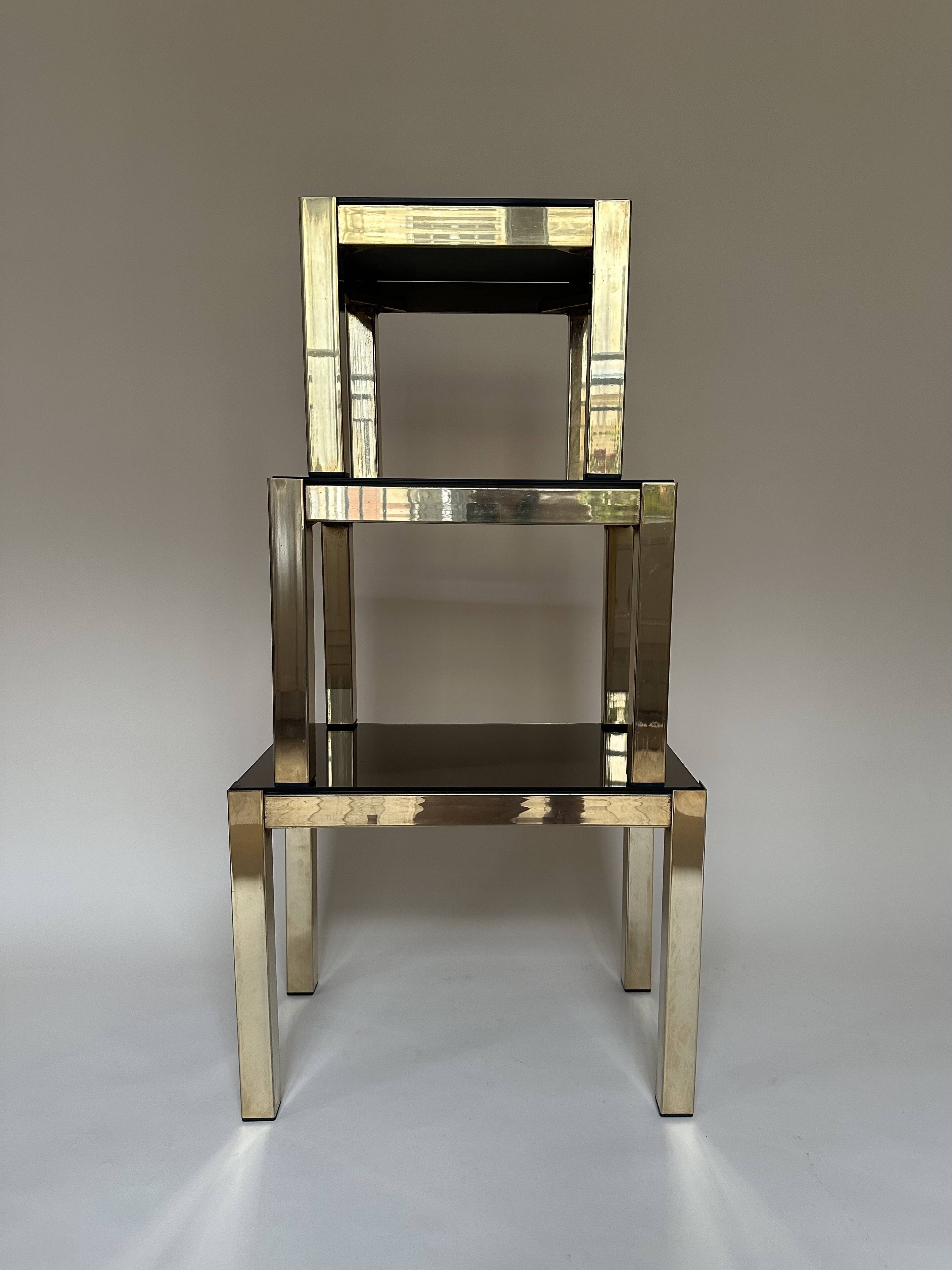 Set of three nesting side tables in brass and smoked mirror.
