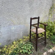 Vintage wooden children's high chair with straw.