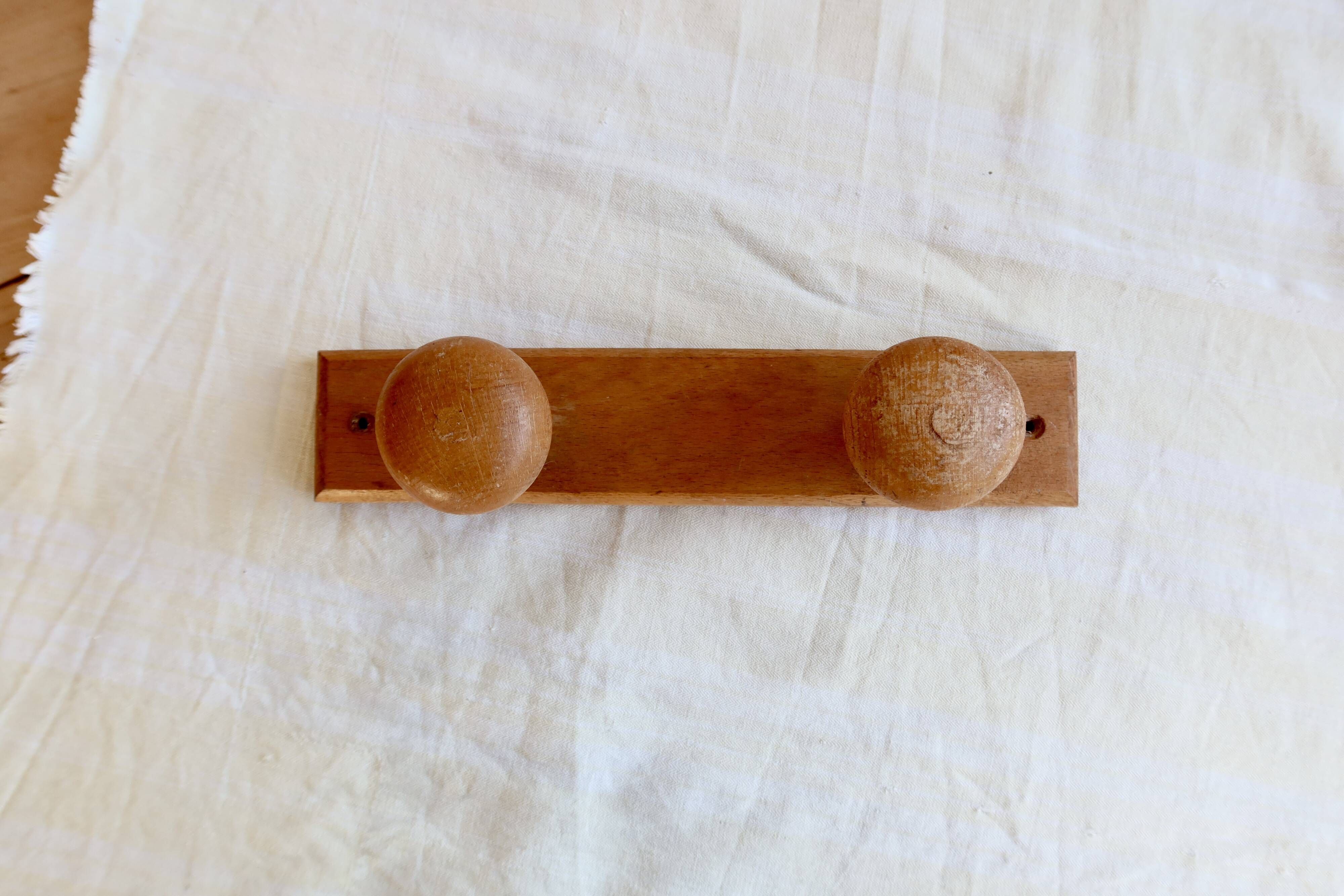 Vintage wooden coat rack with two round hooks.