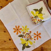 Set of 8 vintage 1970s table napkins with orange and yellow flowers.