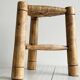 Antique tripod stool in light wood with a woven straw seat.