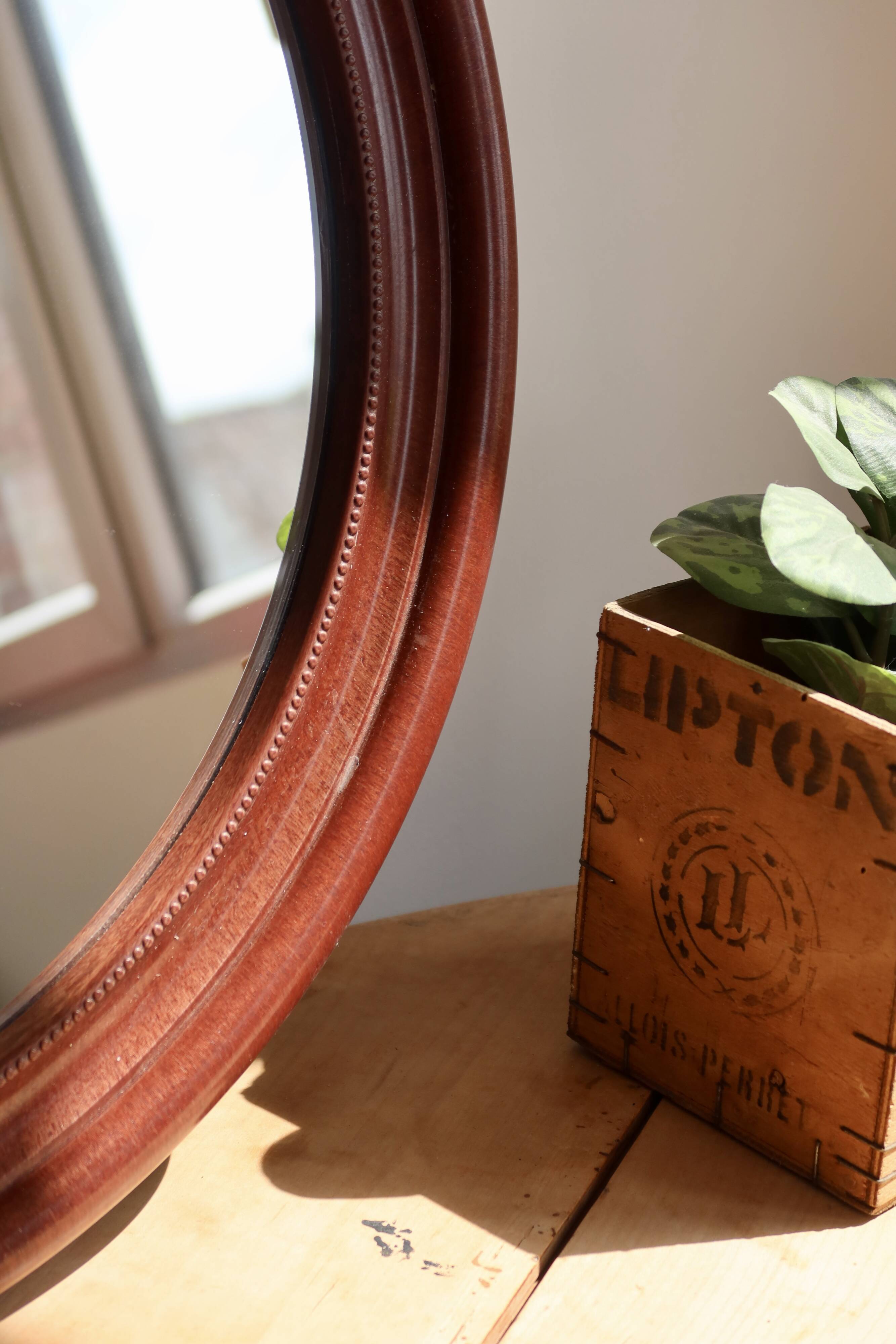 Round vintage mirror with mahogany wood effect frame.