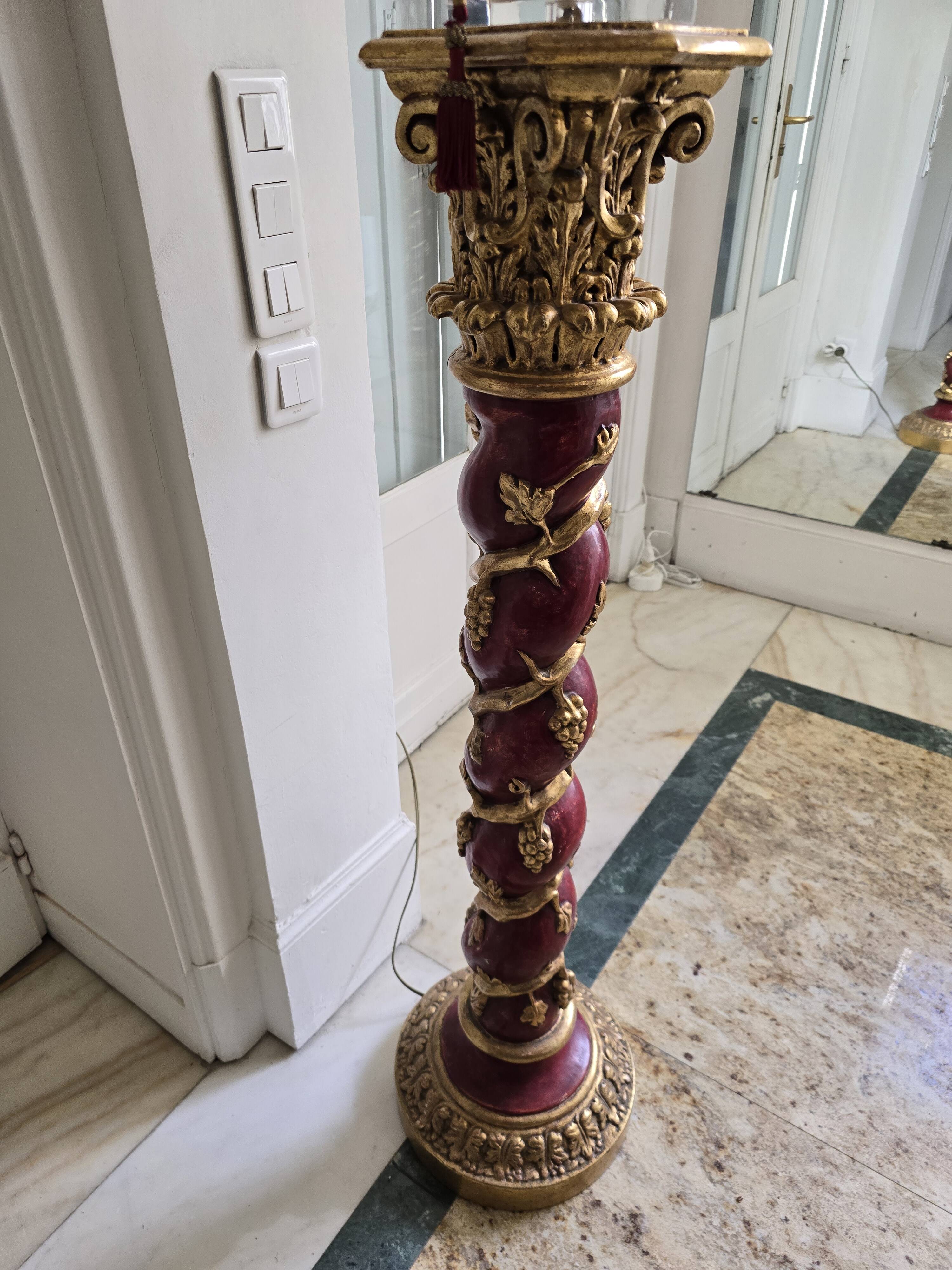red and gold wooden column in the shape of a vine foot topped with a lamp