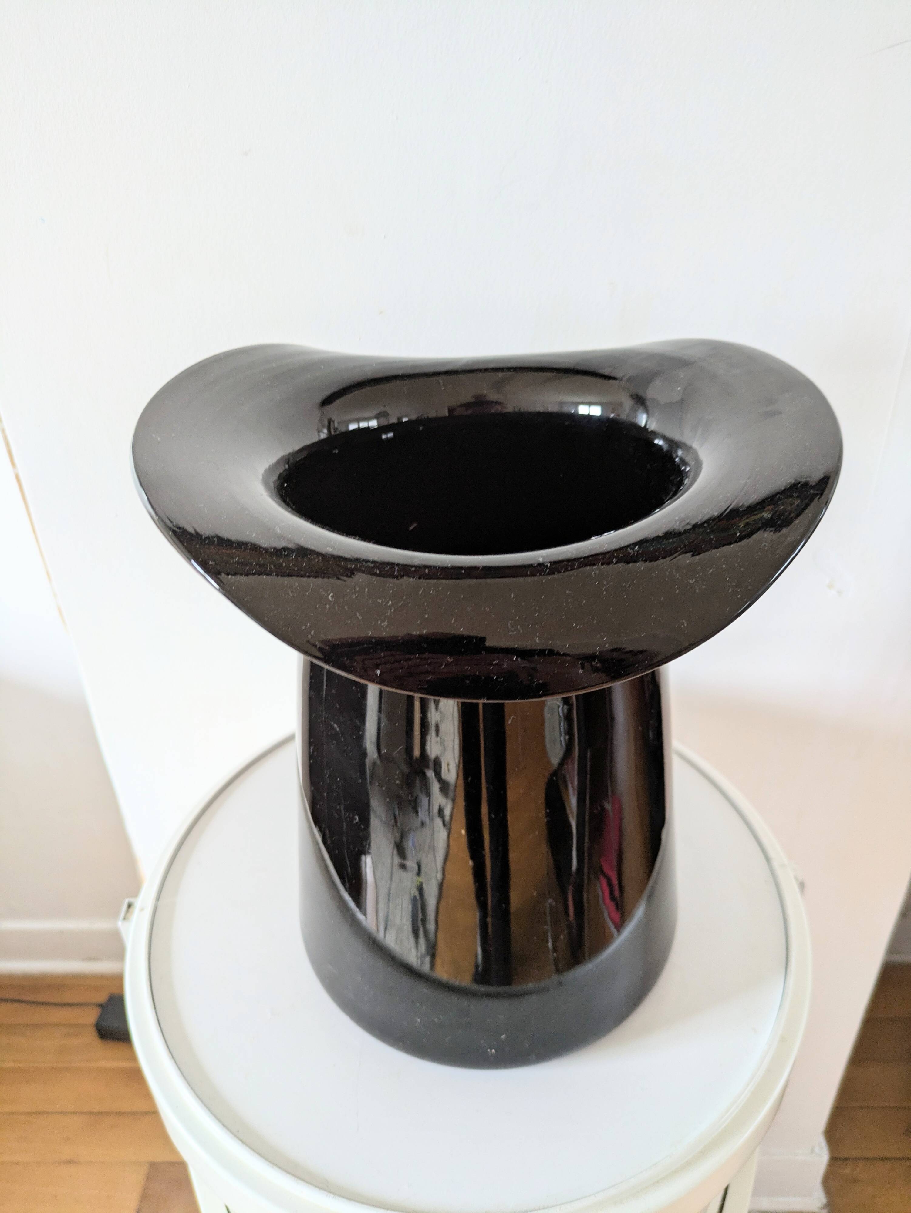 Large black glass vase topped with a 70s hat