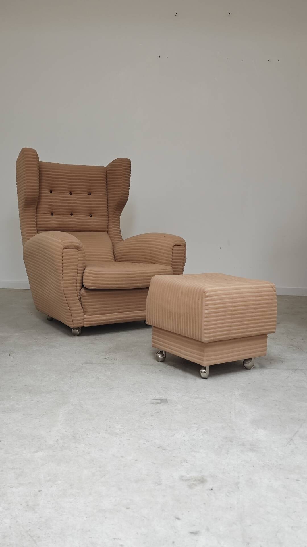 Beige wingback armchair and TVAR footrest, former Czechoslovakia.