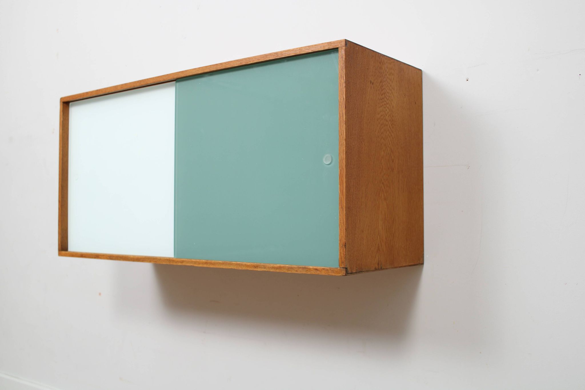 A vintage mid century wall hung bookcase/cabinet with glass sliding doors