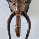 A large Senufo mask made of colored wood, decorated with an anthropomorphic figure