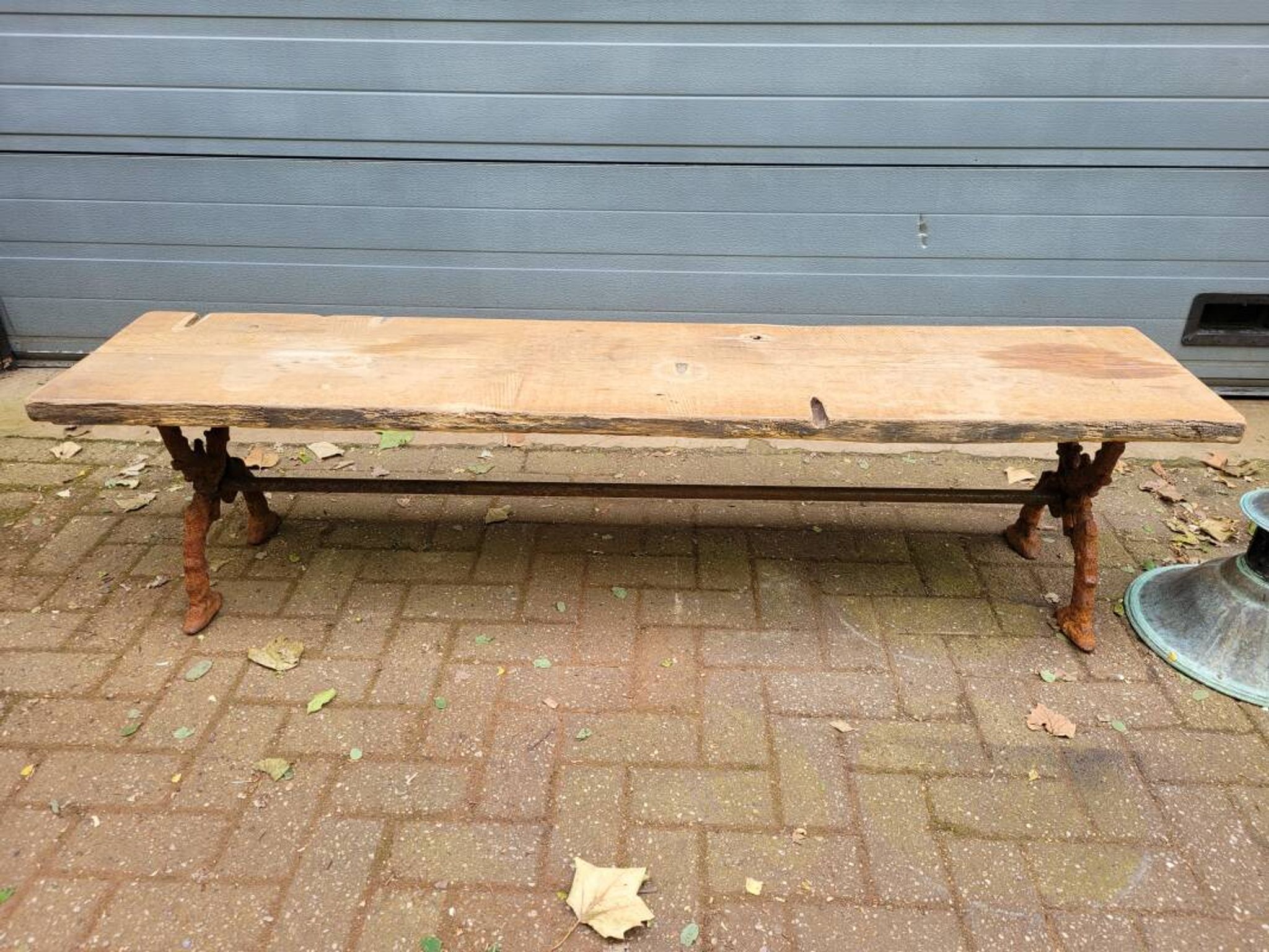 French country-style cast iron garden bench with old barn wood plank.