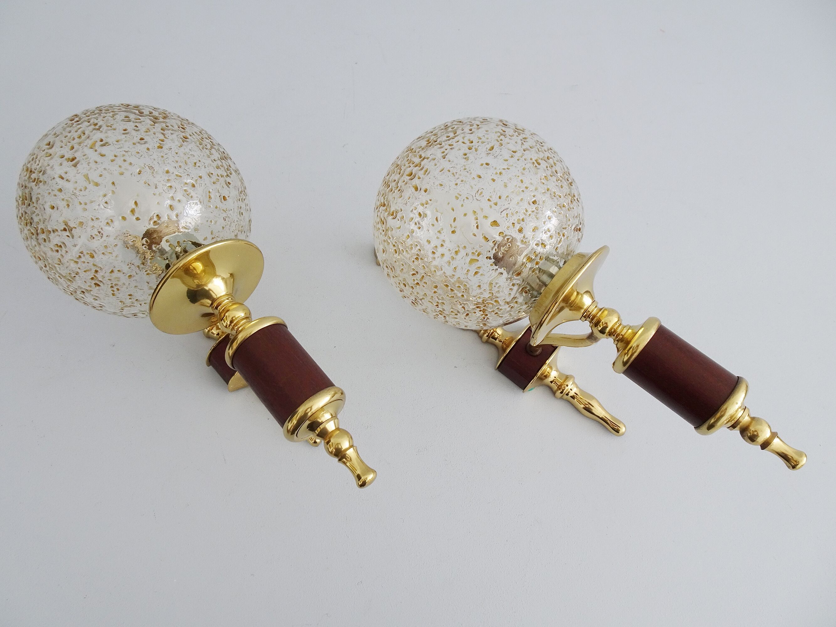 Golden wall lamps with round glass shades and teak veneer