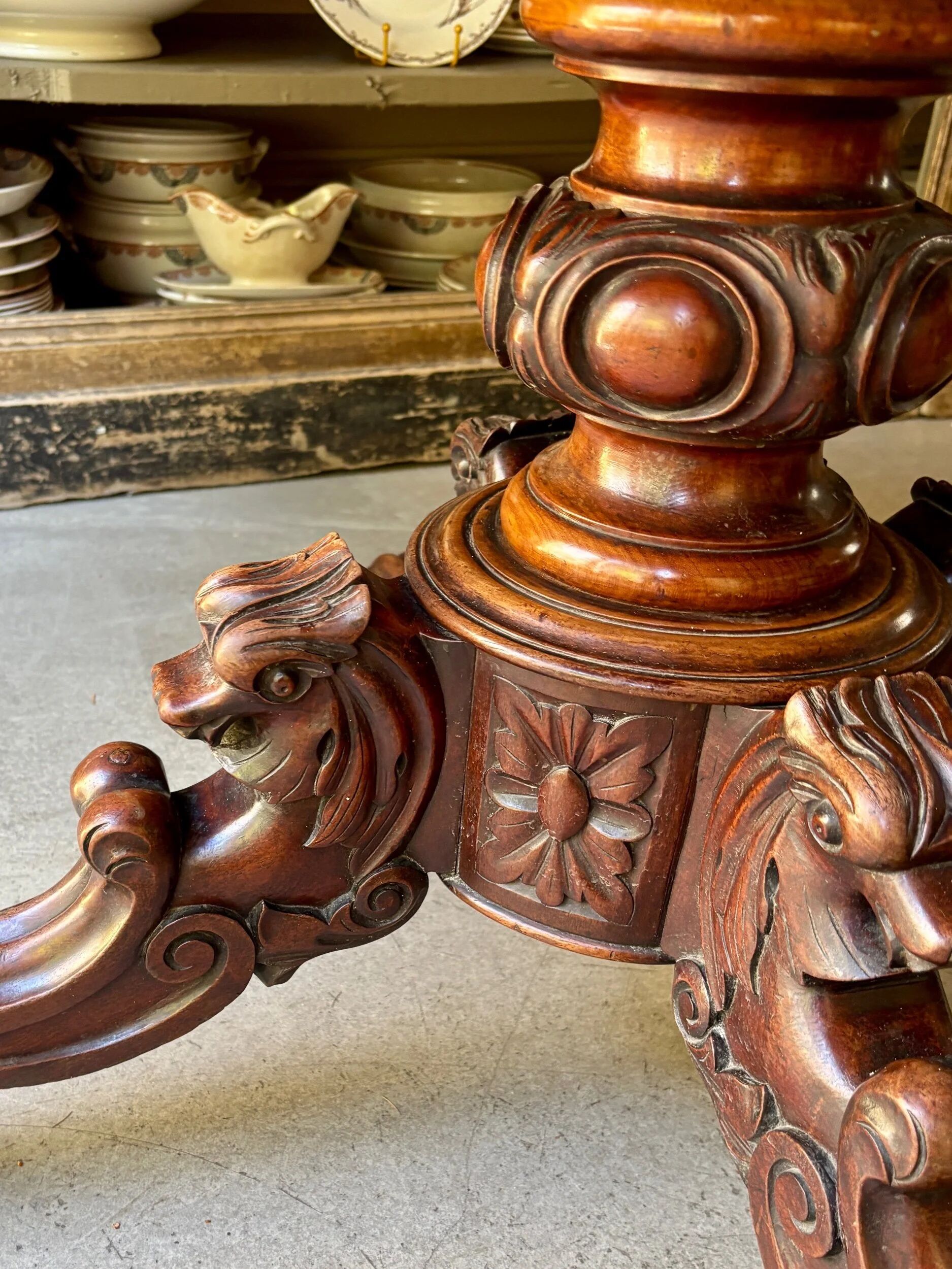 Table with a carved wooden frame and grey marble top on wheels, measuring 130 x 82 cm.