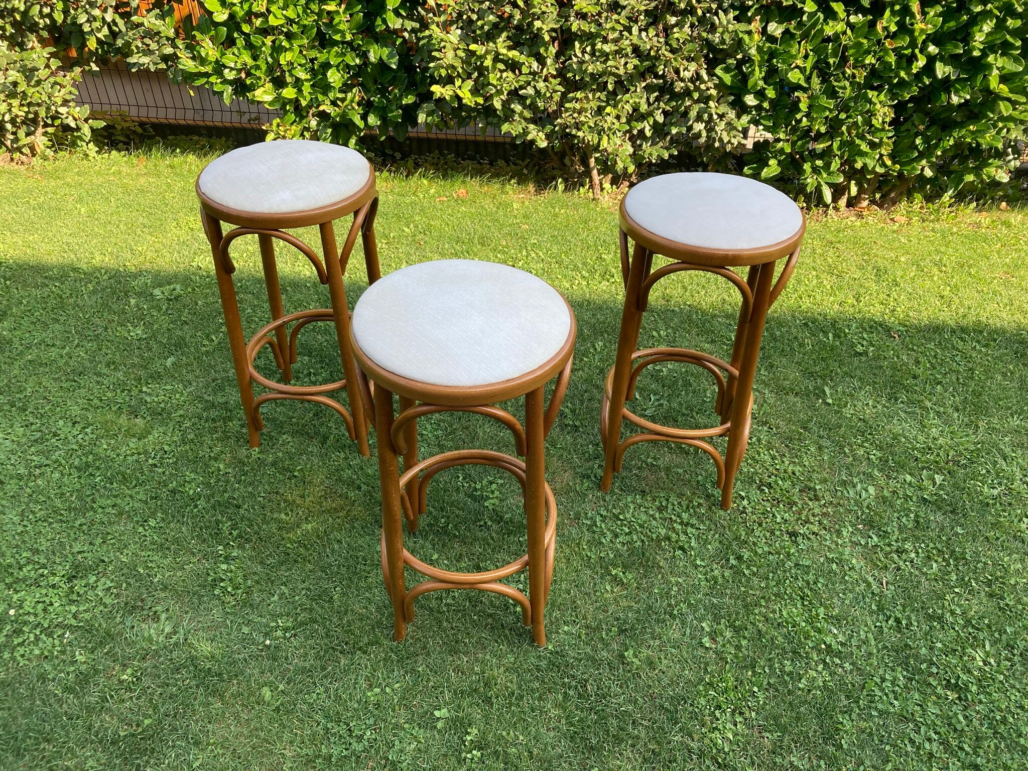 3 bar stools made of curved wood and fabric seat