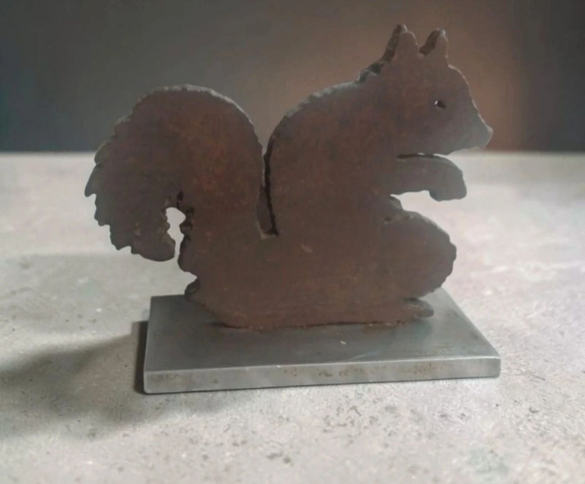 Squirrel bookends in rusty metal on a steel base.