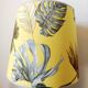Blue ceramic lamp with claw feet and foliage lampshade.