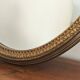 Vintage oval mirror with a carved wooden frame in gold, decorated with a bow.