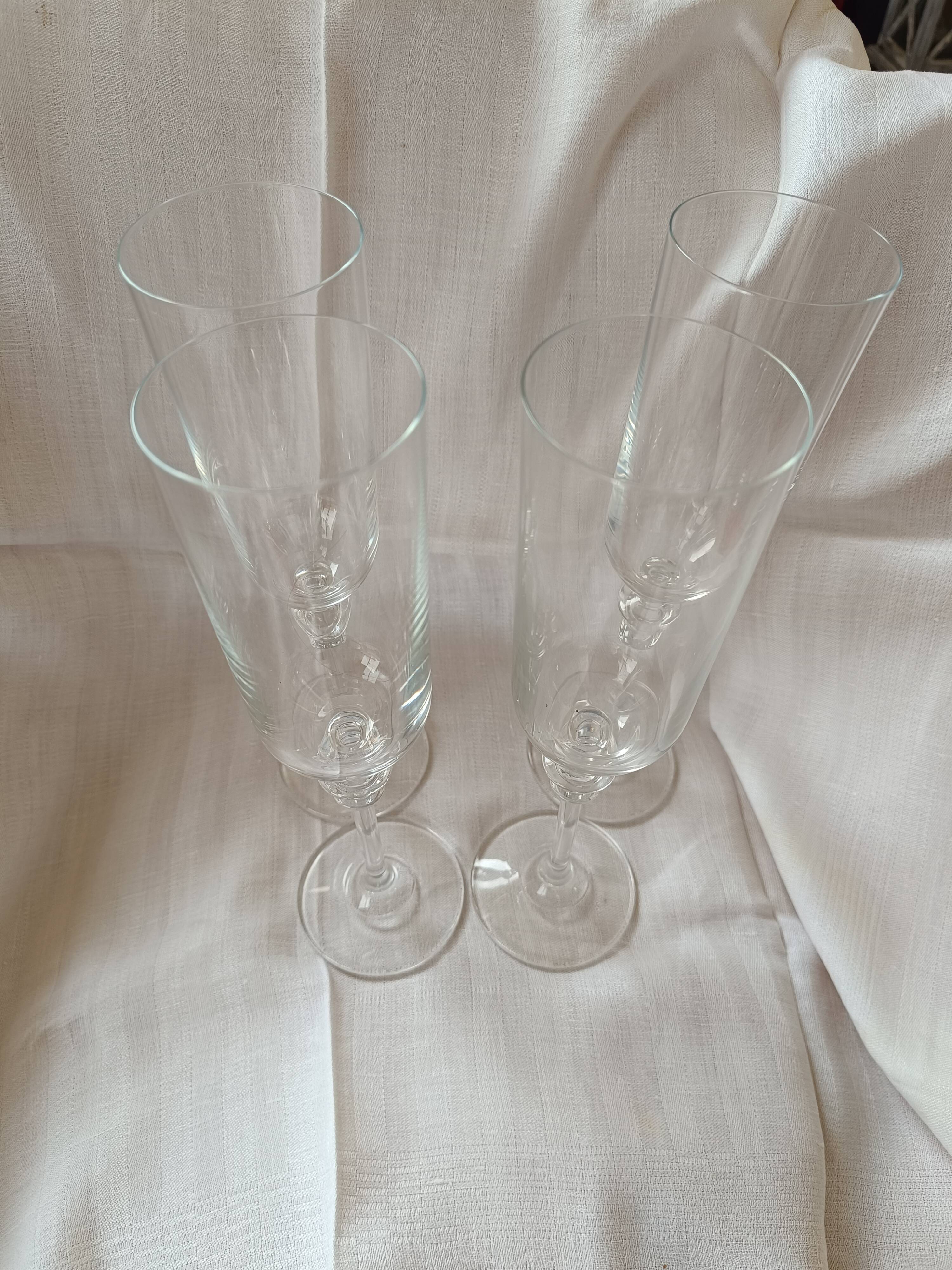 4 crystal champagne flutes with feet decorated with two knots.