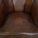Fauteuil club en cuir de mouton foncé avec passepoil noir