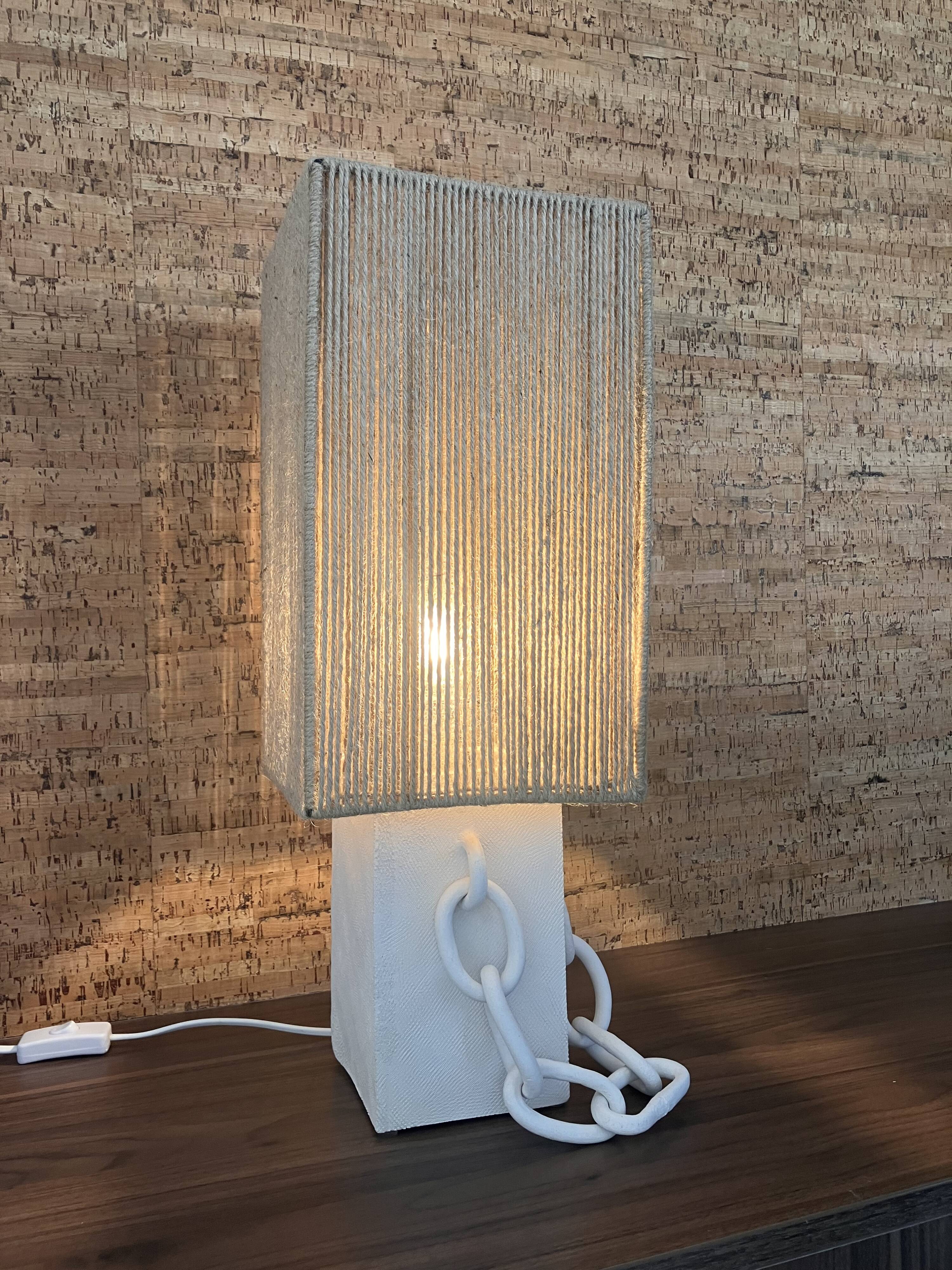 Table lamp in ceramic with decorative chain and cord shade.