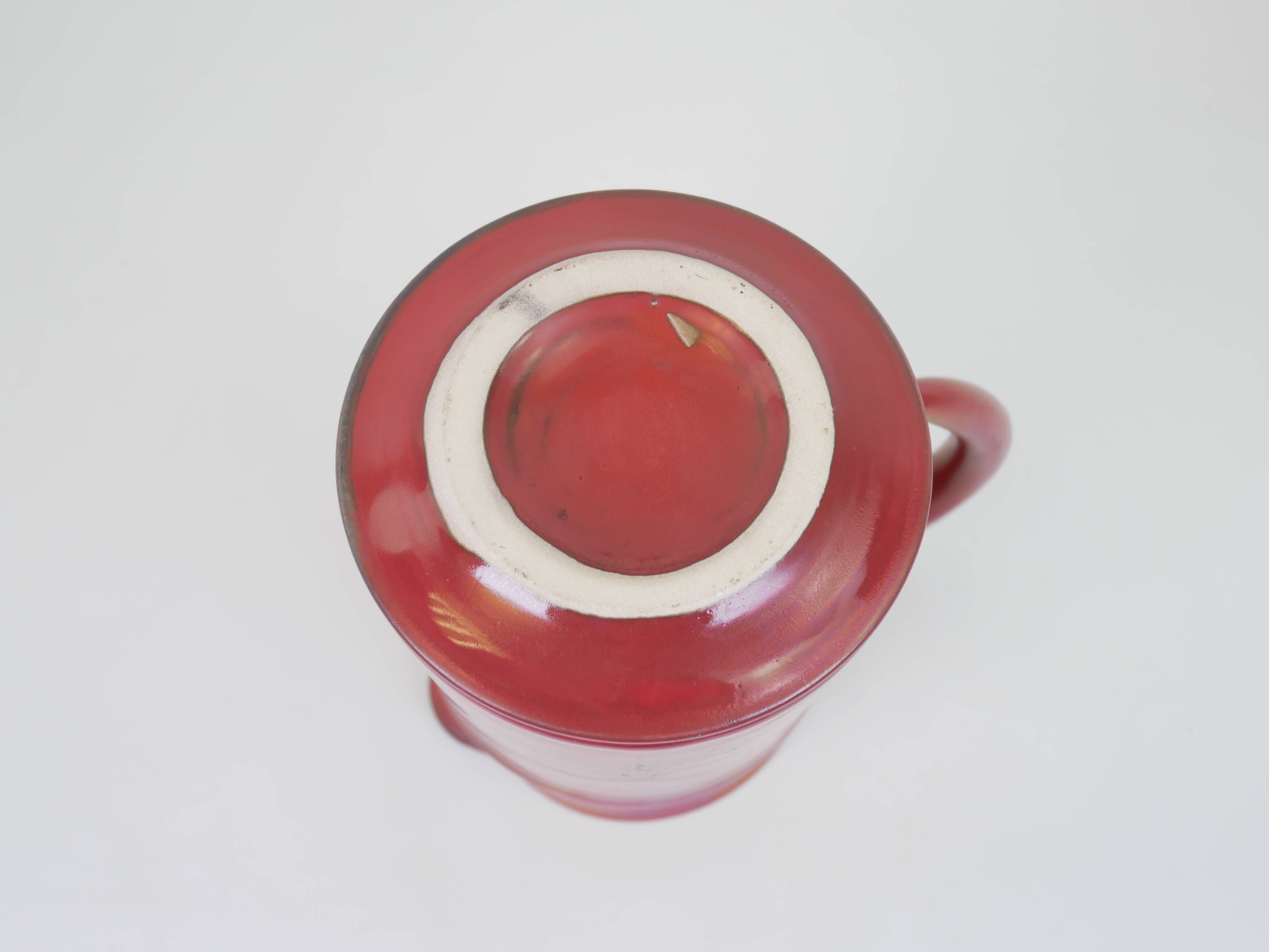 Red glazed ceramic jug with relief