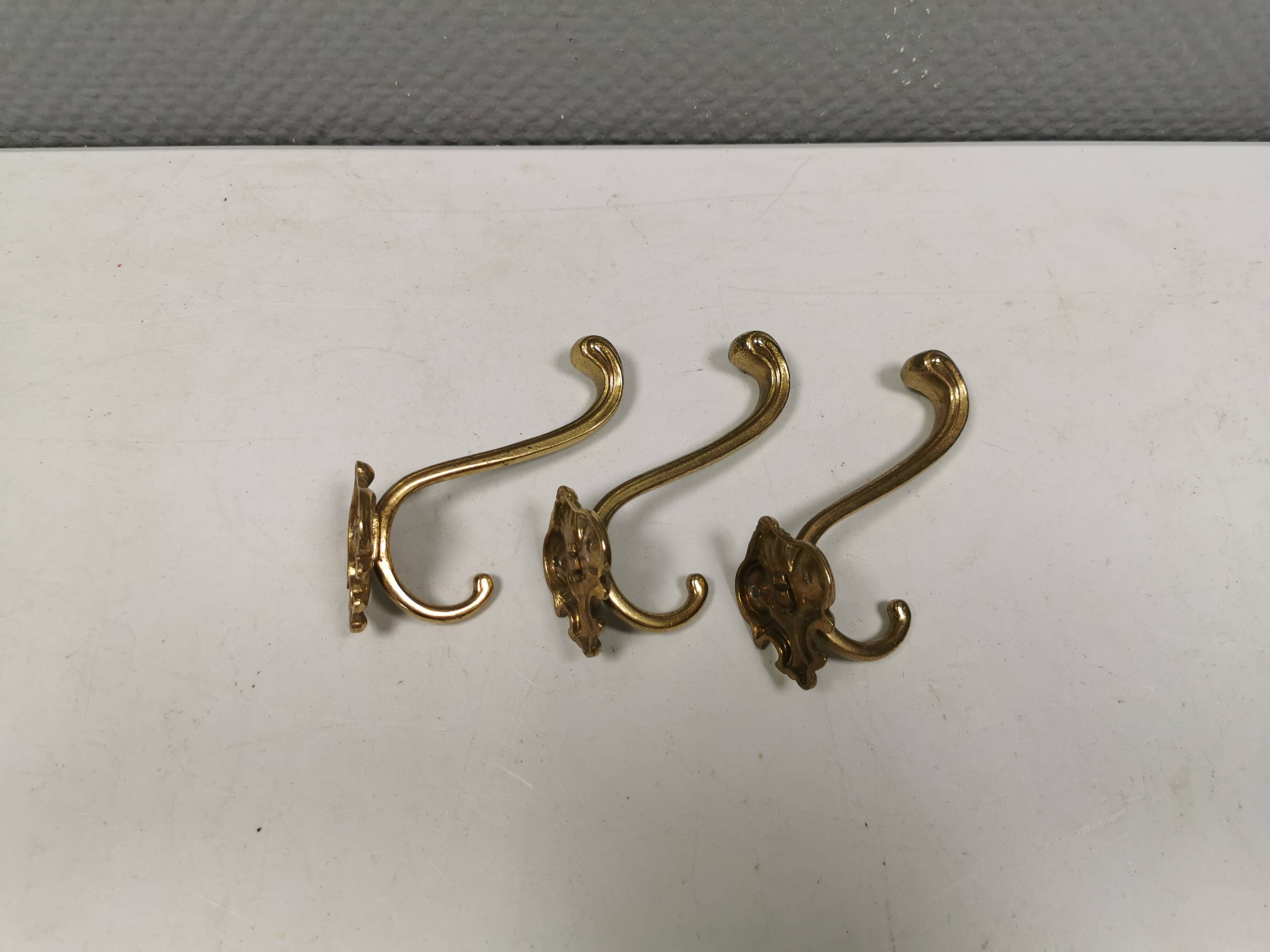Three old and beautiful brass hooks with decorative motifs