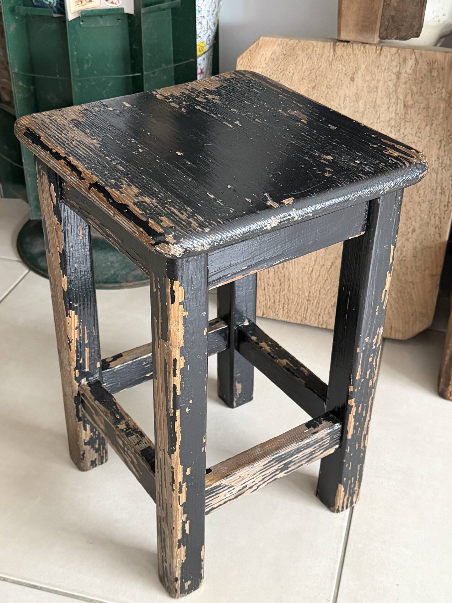 Solid wood stool with a worn black patina.