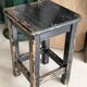 Solid wood stool with a worn black patina.