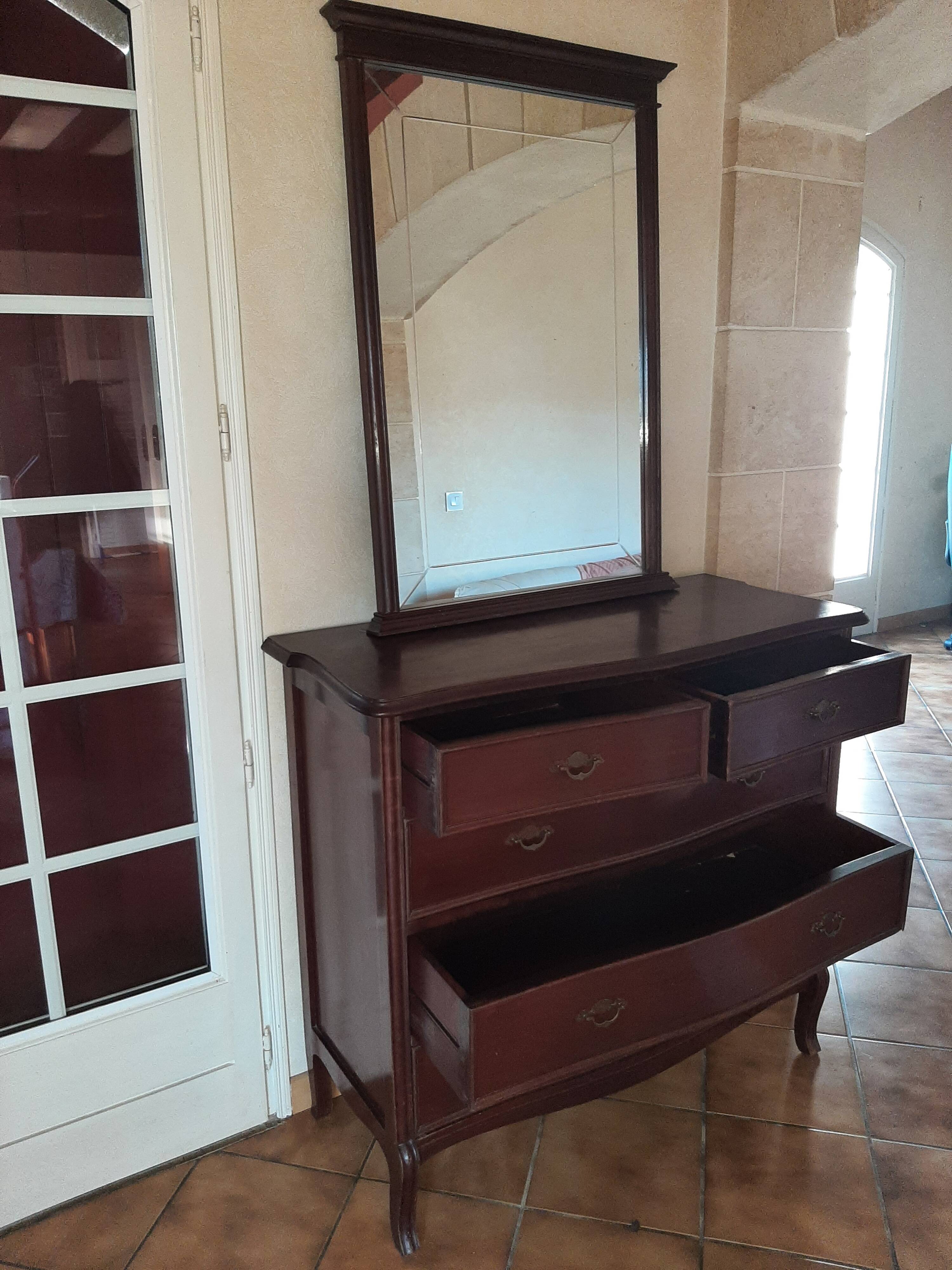 Style set: bevelled mirror and curved wooden chest of drawers.