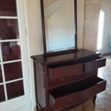 Style set: bevelled mirror and curved wooden chest of drawers.