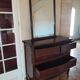 Style set: bevelled mirror and curved wooden chest of drawers.