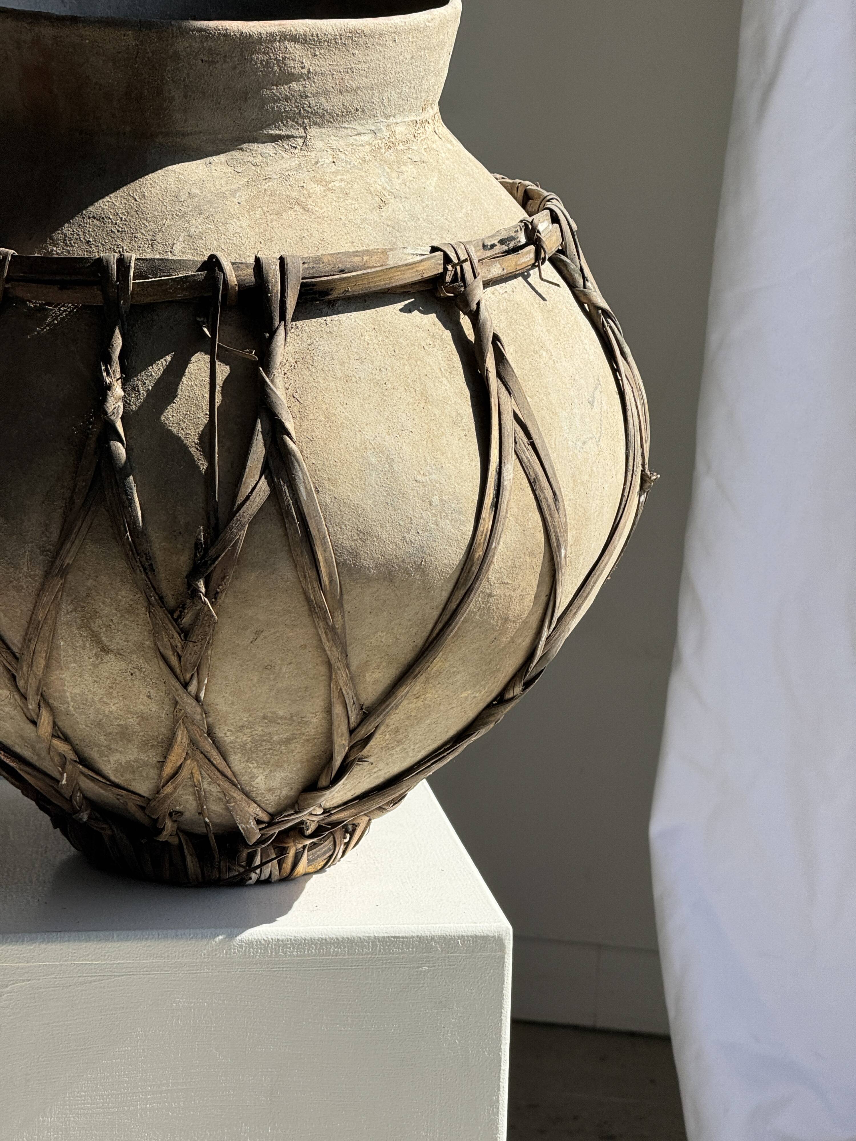 Very large light grey terracotta pot with handles and rattan crossbars.