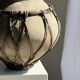 Very large light grey terracotta pot with handles and rattan crossbars.