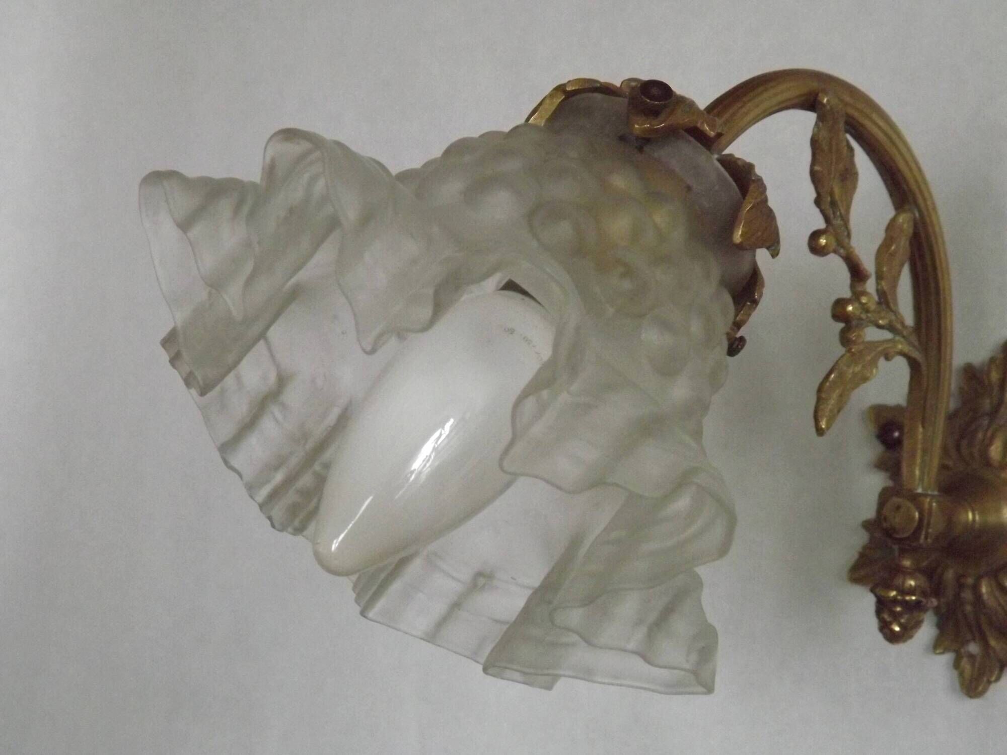 Simple wall sconce in French Art Nouveau bronze with a white glass shade featuring patterns.
