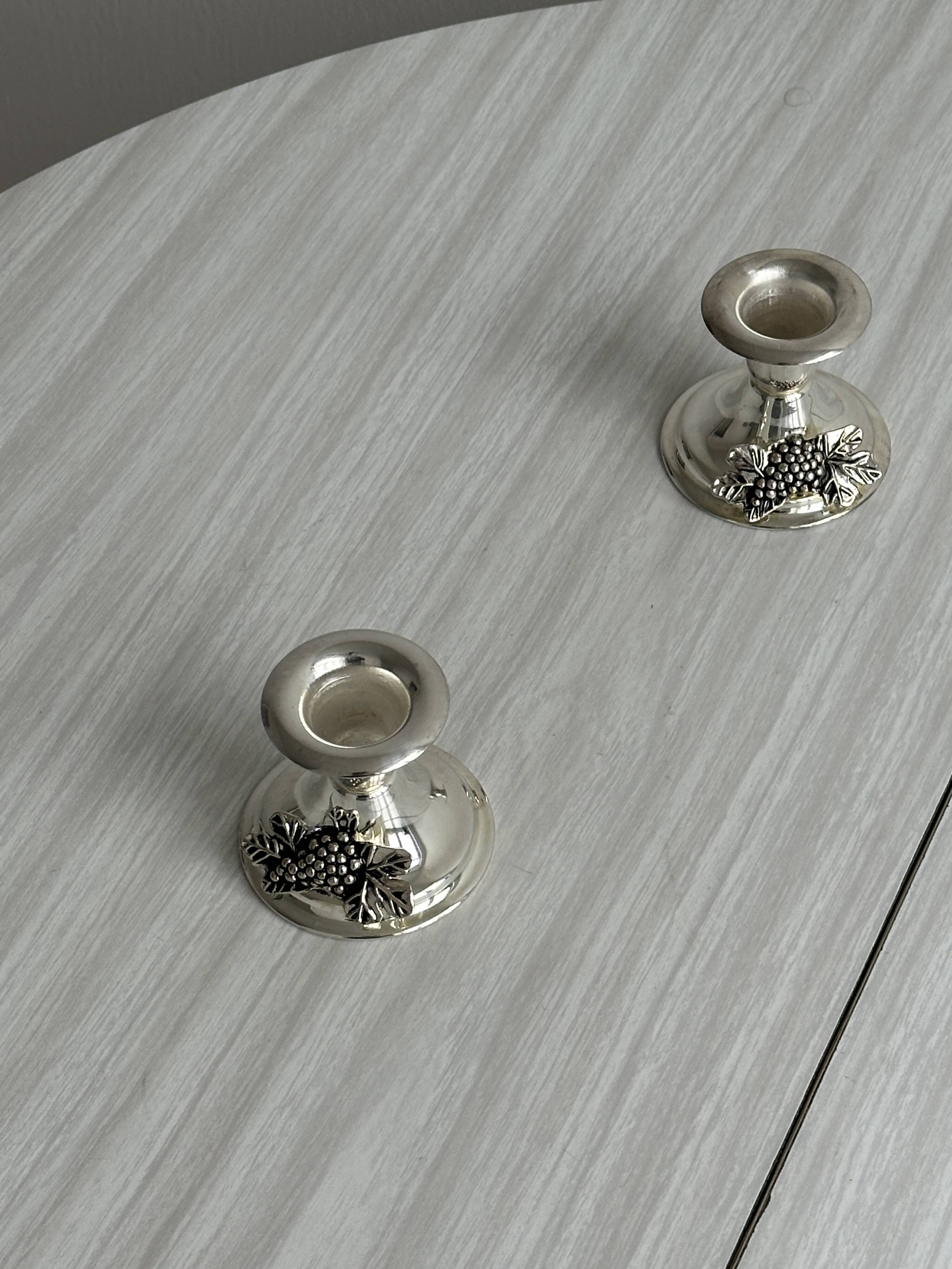 Pair of vintage metal candlesticks with a grape pattern.
