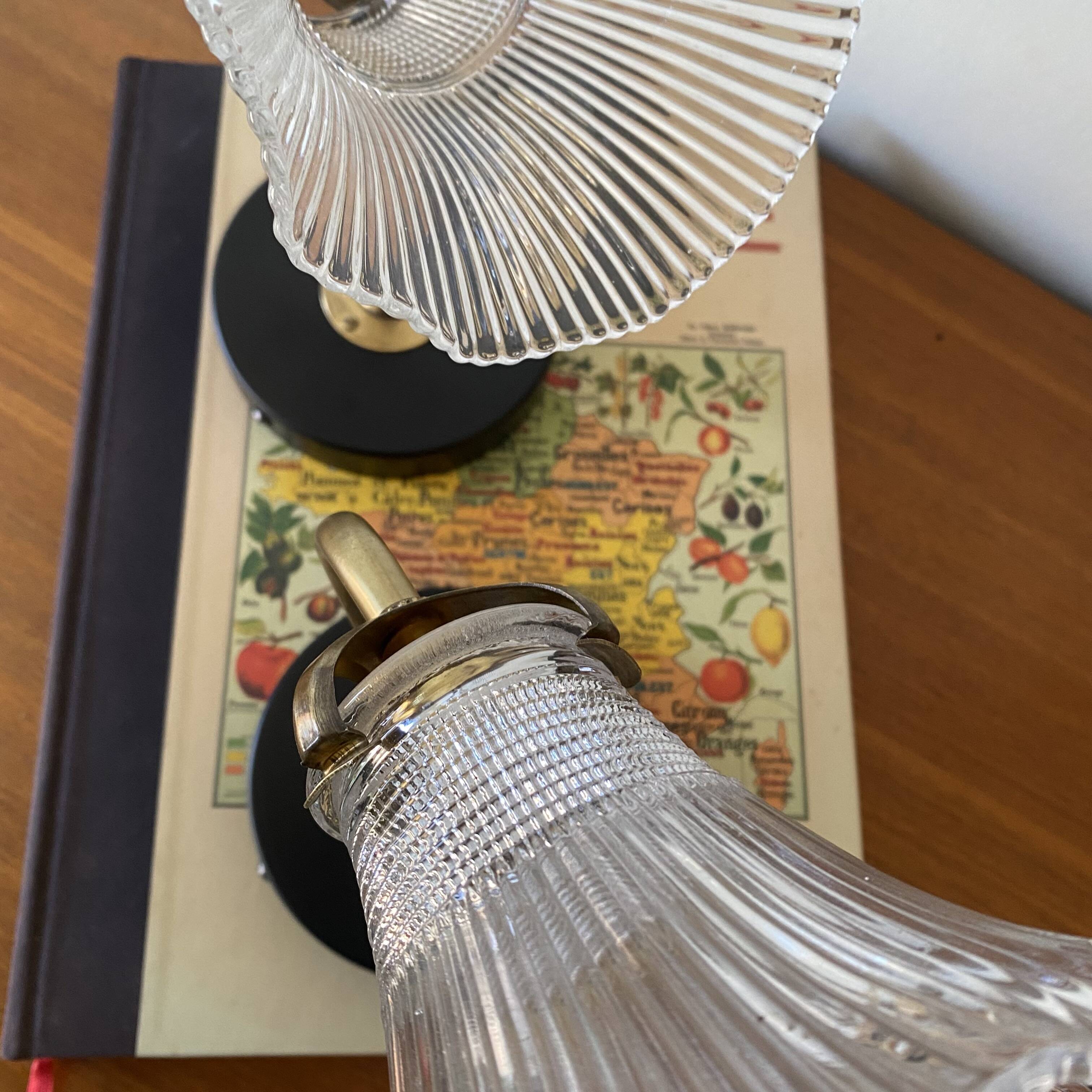 Pair of brass swan neck wall lights with transparent glass shades.