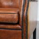 Large sheepskin wingback chair with black piping and decorative nails